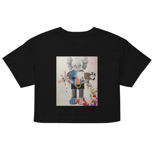 A black short-sleeve crop top t-shirt featuring a central graphic print of a stylized, multi-colored cartoon character resembling KAWS. Daniel Maltzman artist.