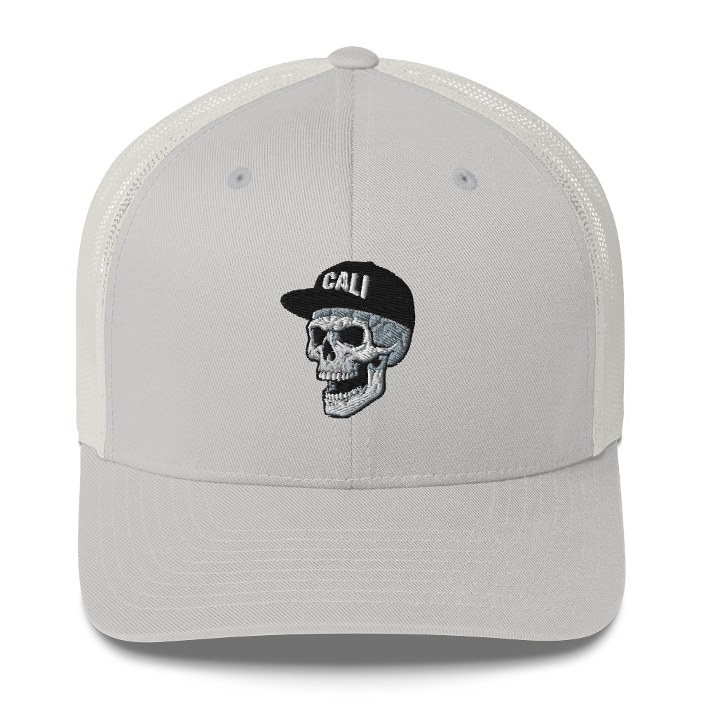 A light gray trucker cap with a white mesh back, featuring an embroidered skull wearing a black cap with 'CALI' on the front.