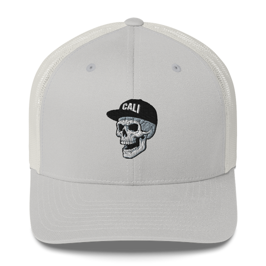 A light gray trucker cap with a white mesh back, featuring an embroidered skull wearing a black cap with 'CALI' on the front.