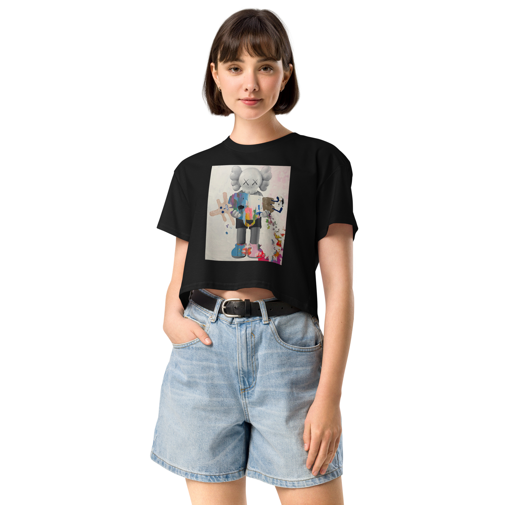 A woman modeling a black crop top t-shirt with a colorful graphic print of a cartoon character, paired with light-wash denim shorts. Daniel Maltzman artist. 