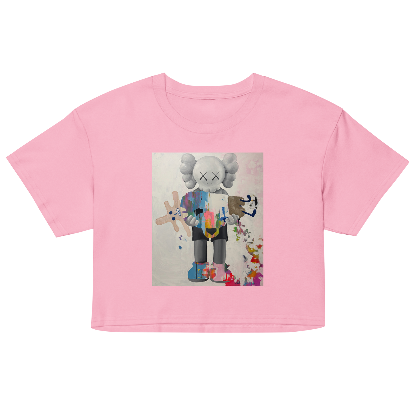 A pink short-sleeve crop top t-shirt featuring a central graphic print of a stylized cartoon character resembling KAWS, Daniel Maltzman artist.