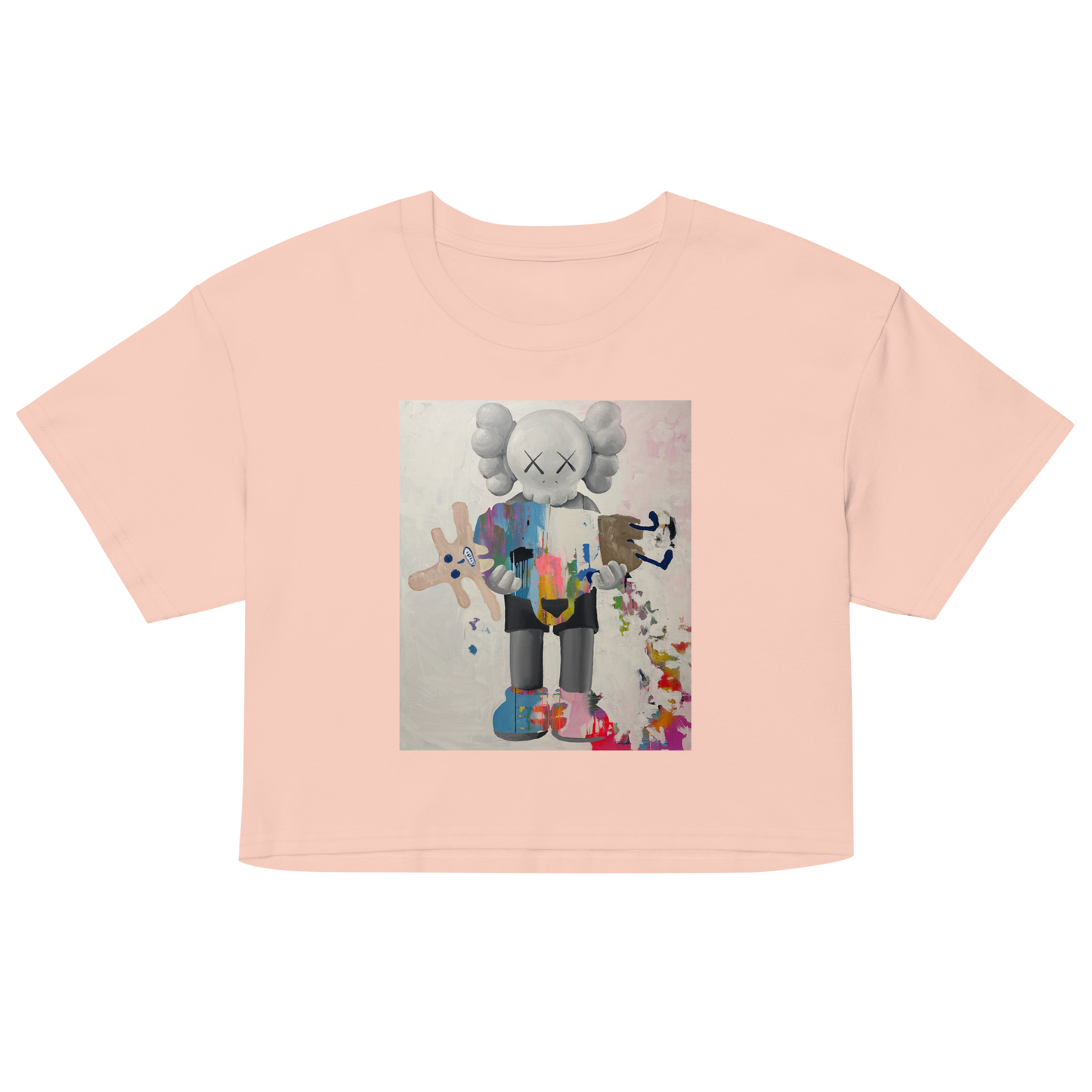 A light peach-pink short-sleeve crop top featuring a central graphic print of a stylized cartoon character with a gray helmet and multicolored clothing, Daniel Maltzman artist.