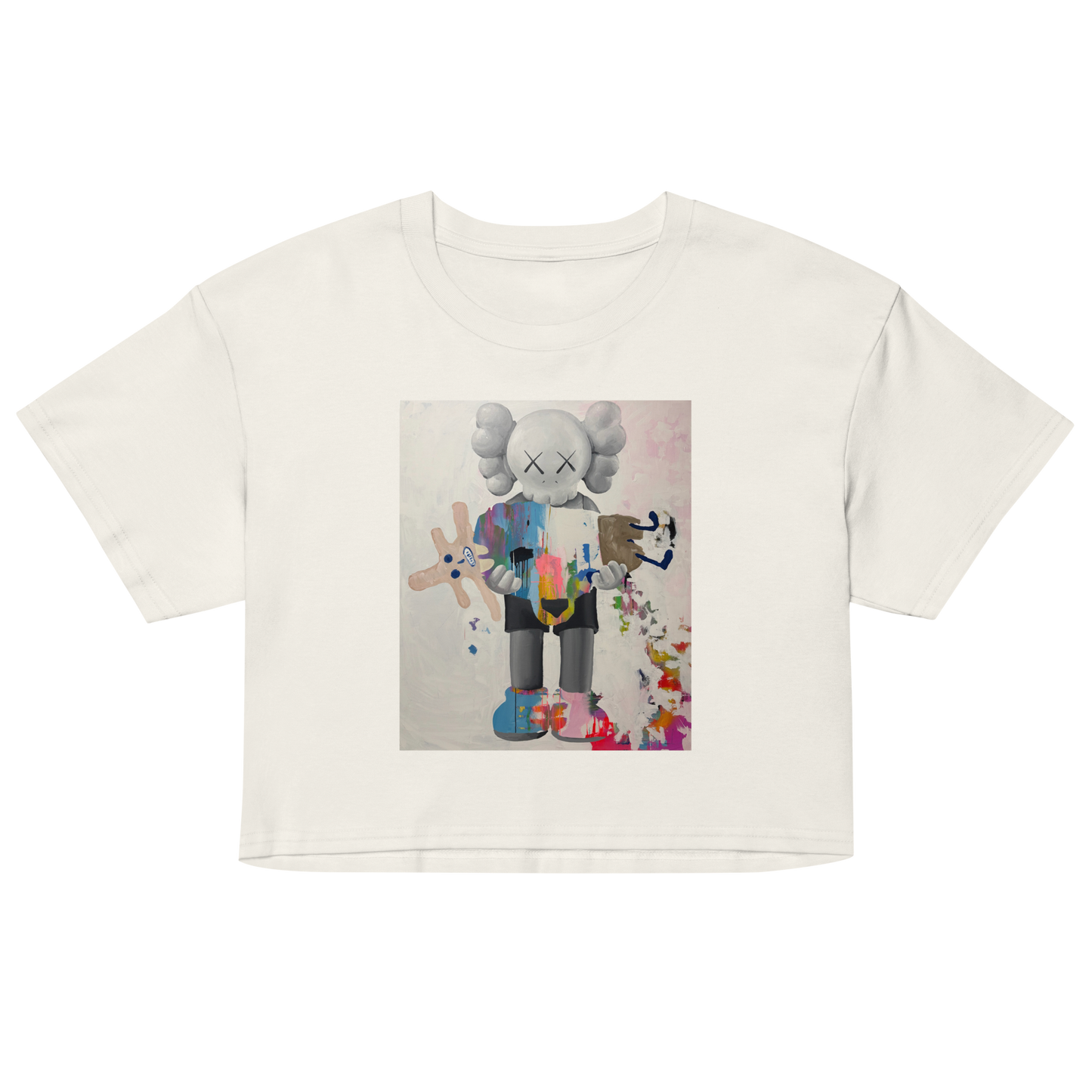 An off-white short-sleeve crop top t-shirt featuring a colorful graphic print of a stylized cartoon character resembling KAWS, Daniel Maltzman artist. 