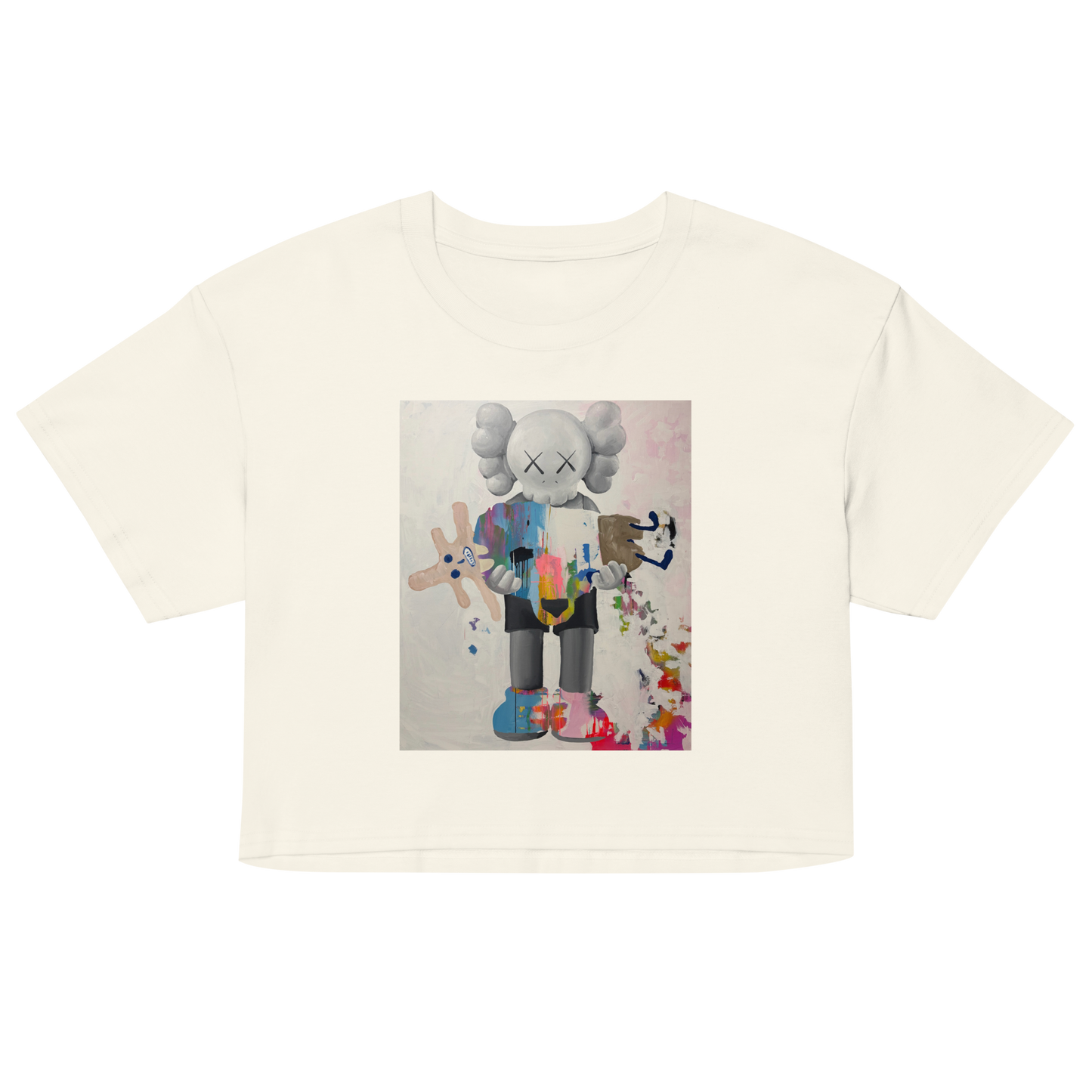 An off-white short-sleeve crop top featuring a colorful graphic print of a stylized character resembling KAWS, displayed on a clean white background.