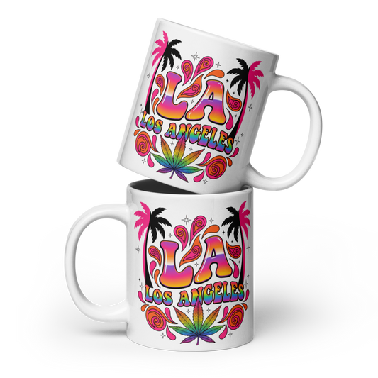 Two white ceramic mugs stacked with a colorful 'LA Los Angeles' graphic featuring palm trees, psychedelic swirls, and a cannabis leaf design, on a white background.