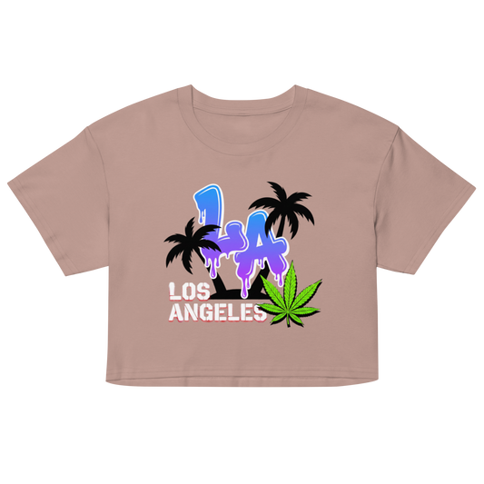 A cropped short-sleeve t-shirt in a dusty rose or mauve color, featuring a colorful graphic print on the front with the text 'LA LOS ANGELES' in blue and white, black palm trees, and a green cannabis leaf.