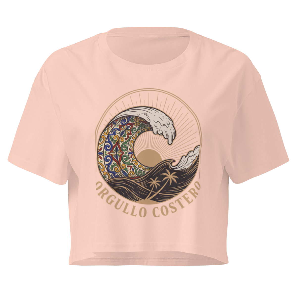 A light peach-pink short-sleeve crop top t-shirt featuring a large graphic print of a stylized wave with a mandala pattern, a sun, palm trees, and the text 'ORGULLO COSTERO' in gold lettering.