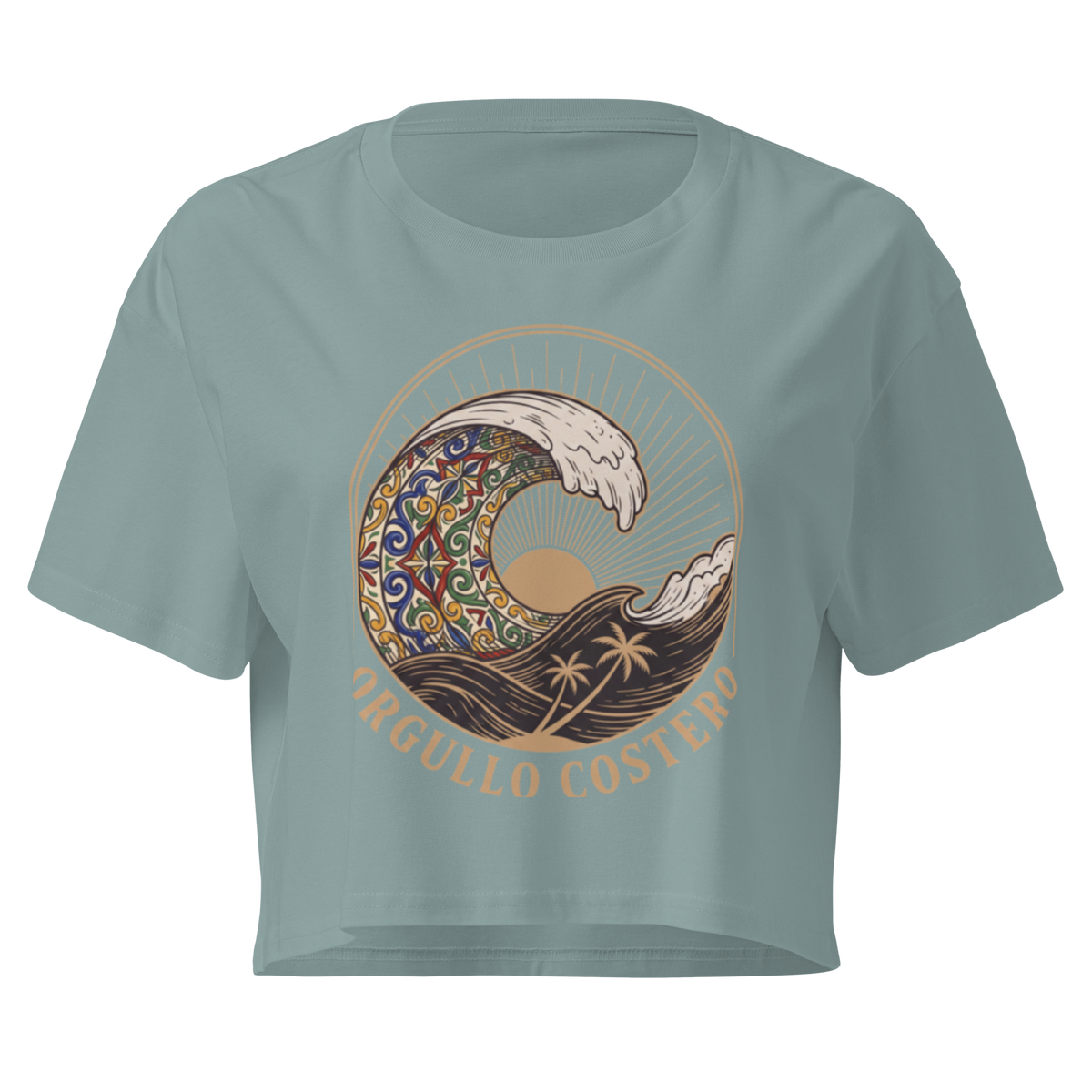 A sage green short-sleeve crop top featuring a large graphic print of a stylized wave with a colorful mandala pattern, a sun, palm trees, and the text 'ORGULLO COSTERO' in tan lettering.