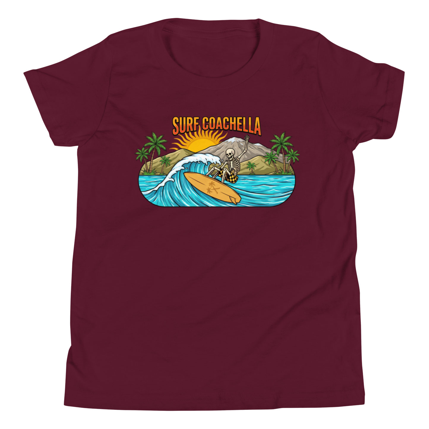A maroon short-sleeve crewneck t-shirt featuring a colorful graphic print of a skeleton surfing on a wave with the text 'SURF COACHELLA' above it.