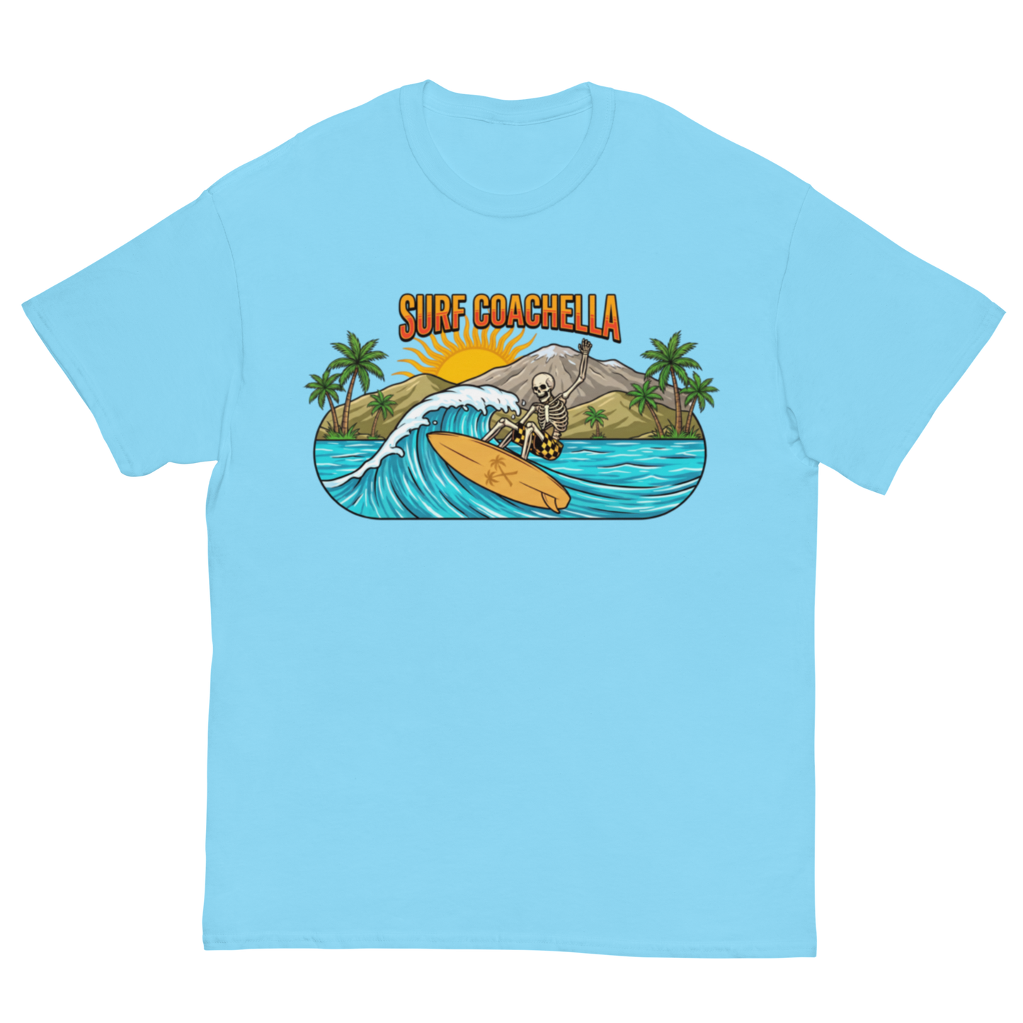 A light blue crewneck t-shirt featuring a colorful graphic print of a skeleton surfer riding a wave on a yellow surfboard, with the text 'SURF COACHELLA' above it and palm trees in the background.