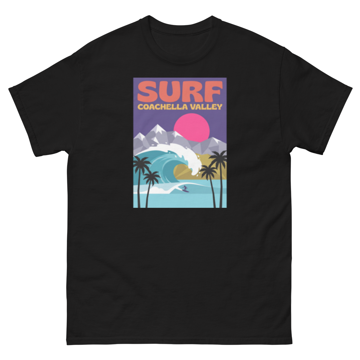 A black short-sleeve crewneck t-shirt featuring a colorful retro-style graphic print on the chest. The graphic displays the text 'SURF COACHELLA VALLEY' in coral and yellow, above an illustration of a surfer riding a turquoise wave with palm trees, a yellow beach, and purple mountains under a pink sun.