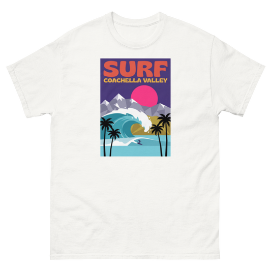 A white short-sleeve crewneck t-shirt featuring a colorful retro-style graphic print on the chest that reads 'SURF COACHELLA VALLEY' above an illustration of a wave, mountains, palm trees, and a pink sun.