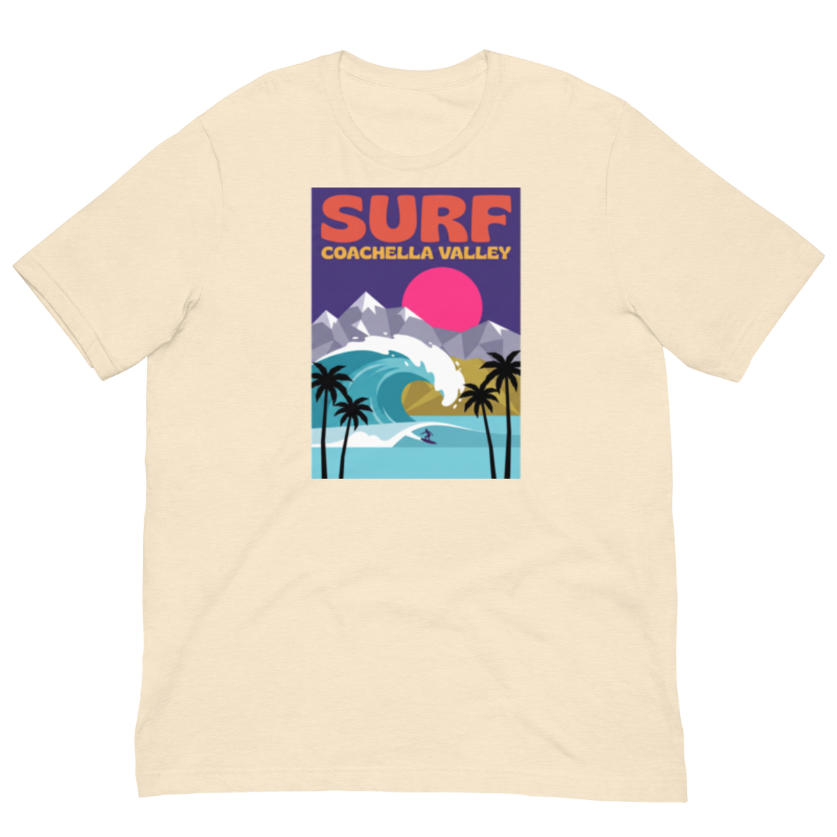 A cream-colored short-sleeve t-shirt with a colorful graphic print on the front. The graphic features the text 'SURF COACHELLA VALLEY' above an illustration of a surfer riding a wave, with palm trees, mountains, and a pink sun.