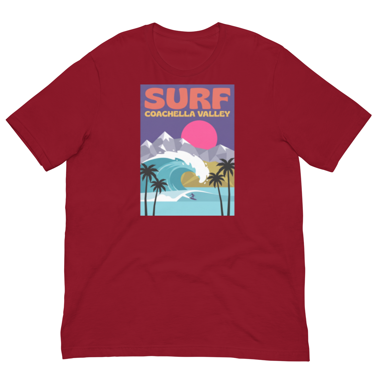 A red short-sleeve crewneck t-shirt featuring a colorful retro-style graphic print on the chest that reads 'SURF COACHELLA VALLEY' above an illustration of a wave, mountains, palm trees, and a pink sun.