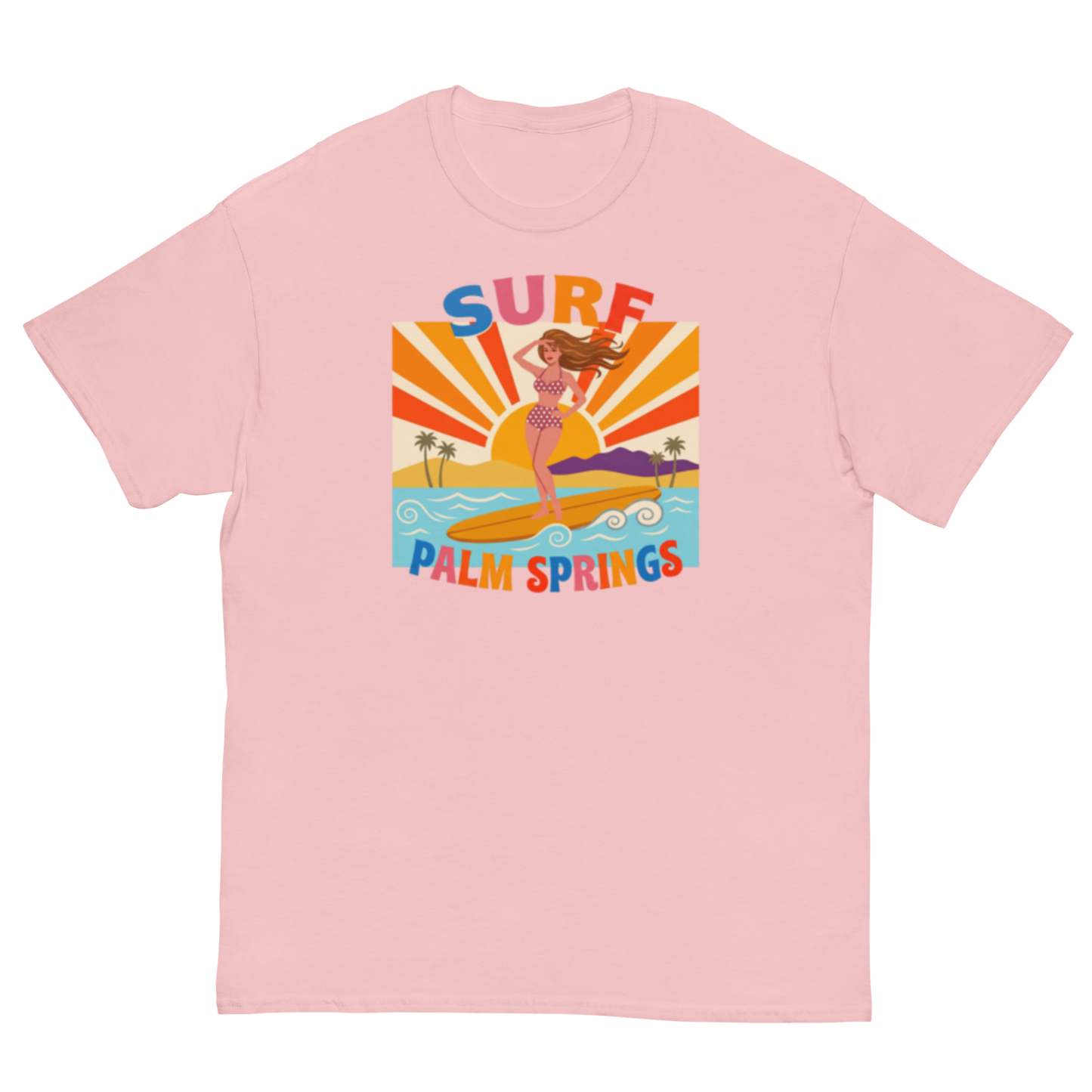A light pink short-sleeve crewneck t-shirt featuring a retro-style graphic of a woman surfing on a yellow board with palm trees and the text 'SURF PALM SPRINGS' in colorful lettering.
