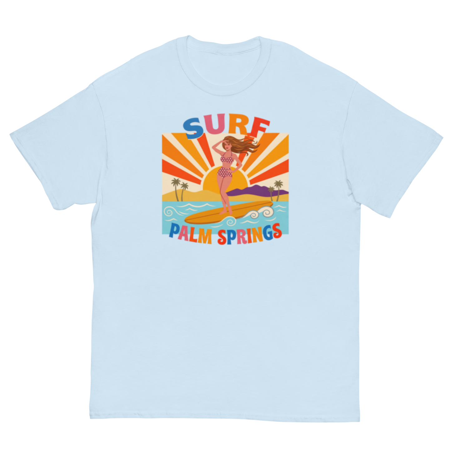 A pale blue crewneck t-shirt featuring a retro-style graphic of a woman surfing on a yellow board with palm trees and the text 'SURF PALM SPRINGS' in colorful letters.
