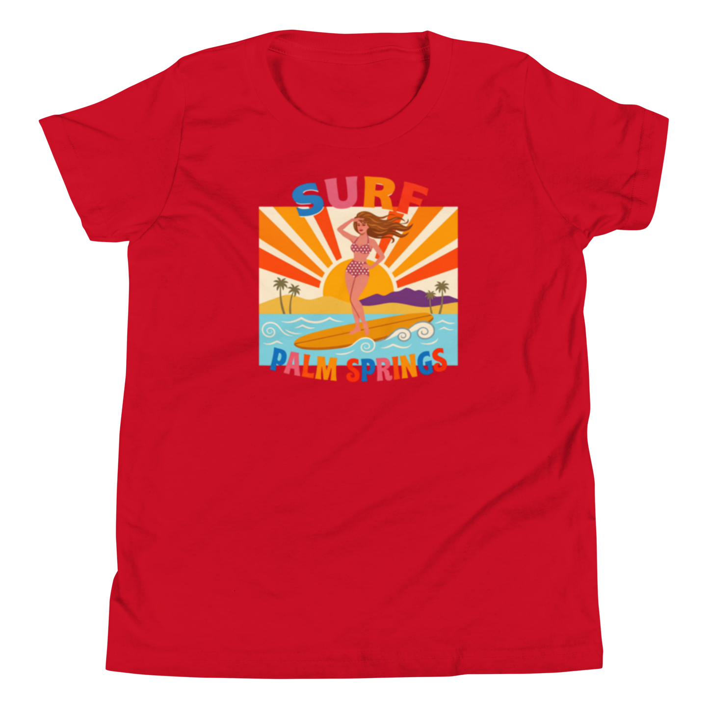 A red short-sleeve crewneck t-shirt featuring a colorful retro graphic of a mermaid surfing on a beach with the text 'SURF PALM SPRINGS'.