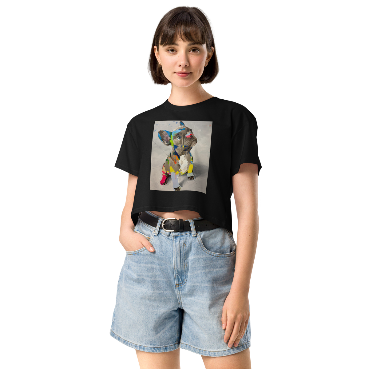 A woman modeling a black short-sleeve crop top t-shirt with a colorful geometric dog graphic on the front, paired with light-wash denim shorts, Daniel Maltzman artist.
