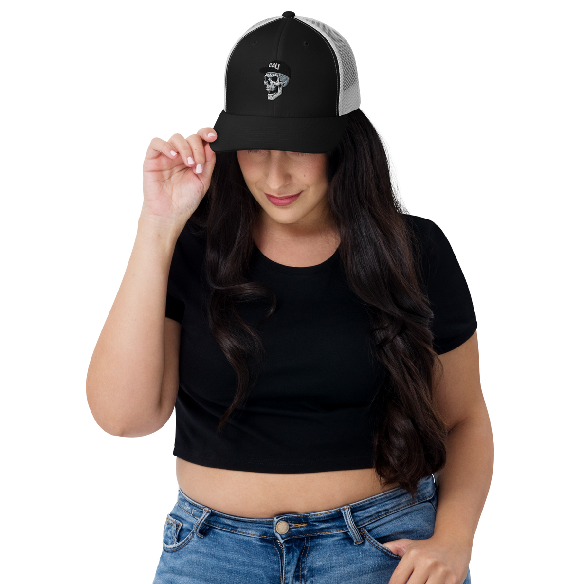 Woman wearing a black cap with a logo and text, black crop top, and blue jeans on a white background