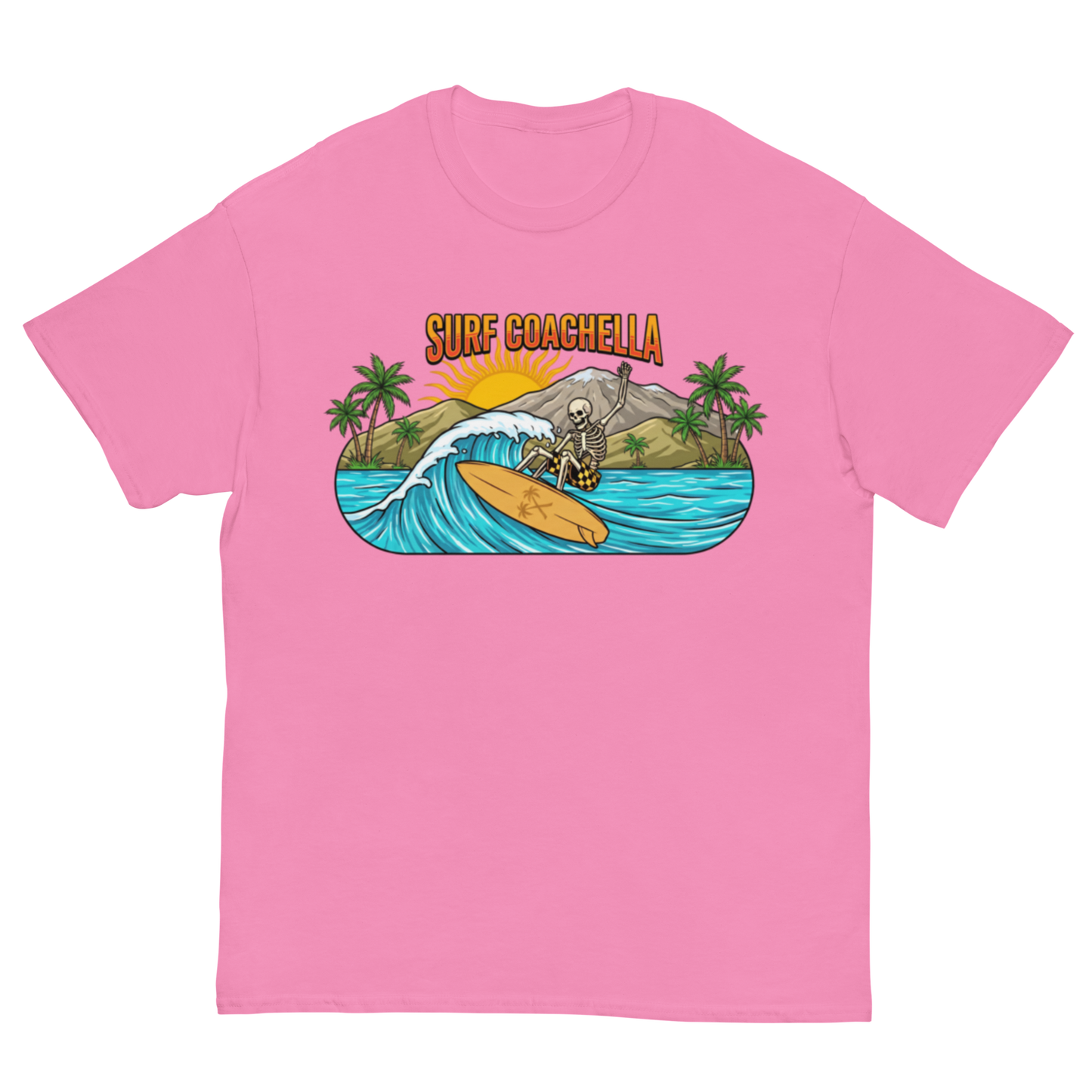 A pink short-sleeve crewneck t-shirt featuring a colorful graphic print on the chest. The graphic shows a skeleton surfing on a wave with palm trees, a mountain, and the text 'SURF COACHELLA' in orange above it, set against a plain white background.