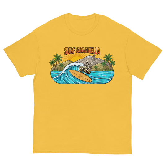 A yellow short-sleeve crewneck t-shirt featuring a colorful graphic print on the chest. The graphic shows a skeleton surfer riding a wave on a beach with palm trees and the text 'SURF COACHELLA' in orange.