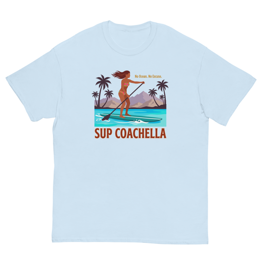 A light blue crewneck t-shirt featuring a colorful graphic of a woman paddleboarding on tropical water with palm trees and the text 'No Ocean, No Excuse.' and 'SUP COACHELLA'.