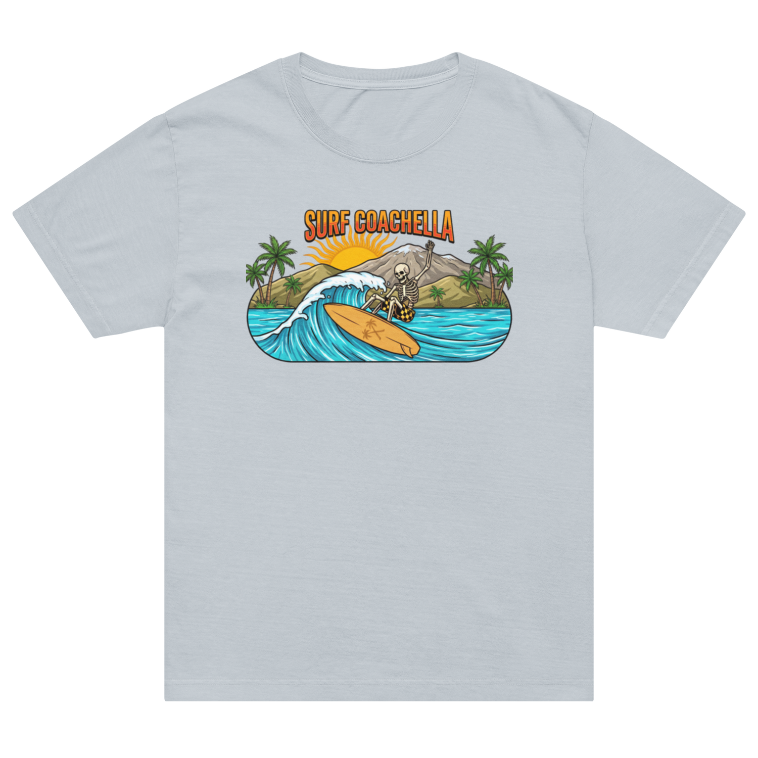 A light gray crewneck t-shirt featuring a colorful graphic print on the chest. The graphic depicts a skeleton surfing on a yellow board on a turquoise wave, with palm trees, a mountain, and the text 'SURF COACHELLA' above it.
