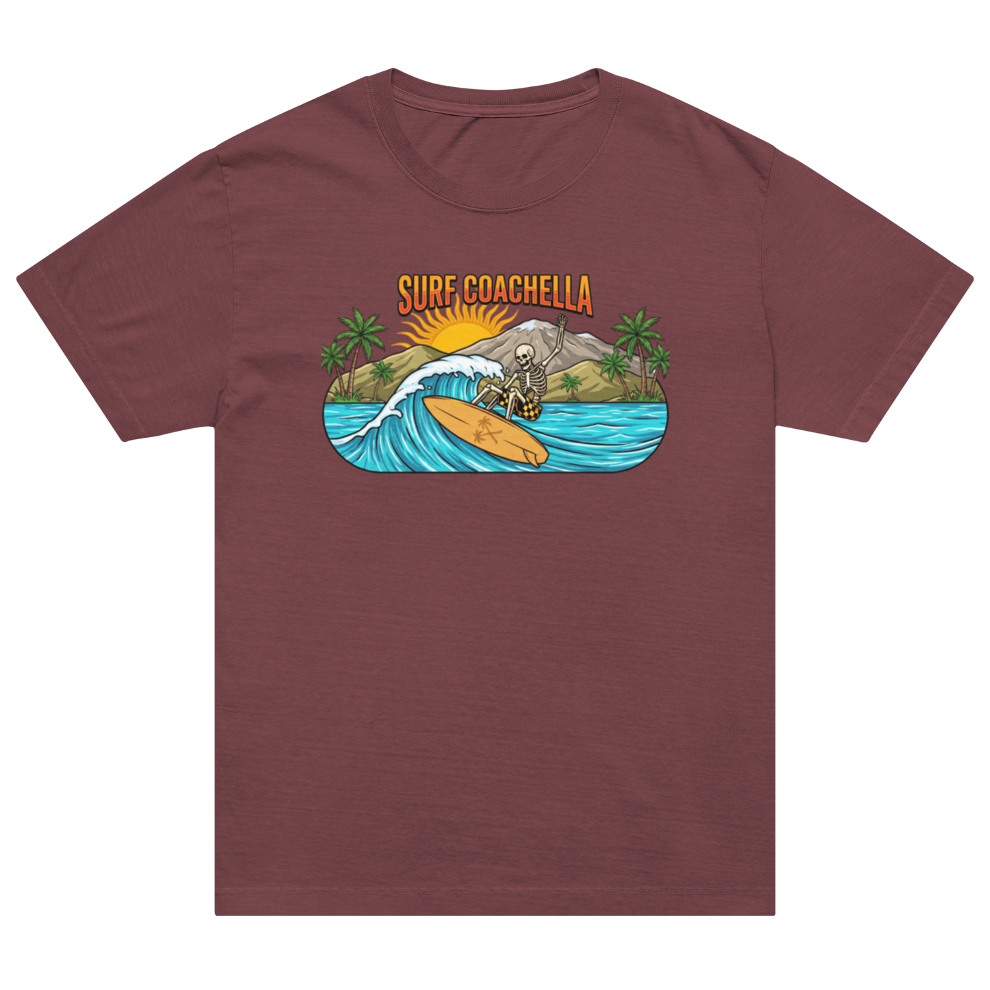 A maroon short-sleeve crewneck t-shirt featuring a colorful graphic print on the chest. The graphic shows a skeleton surfer riding a wave with the text 'SURF COACHELLA' above it, set against a plain white background.