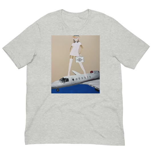 A light heather gray short-sleeve t-shirt with a central graphic print. The print features a cartoon illustration of a woman in a white dress and hat walking on top of a white and blue private jet against a beige background. Daniel Maltzman artist.
