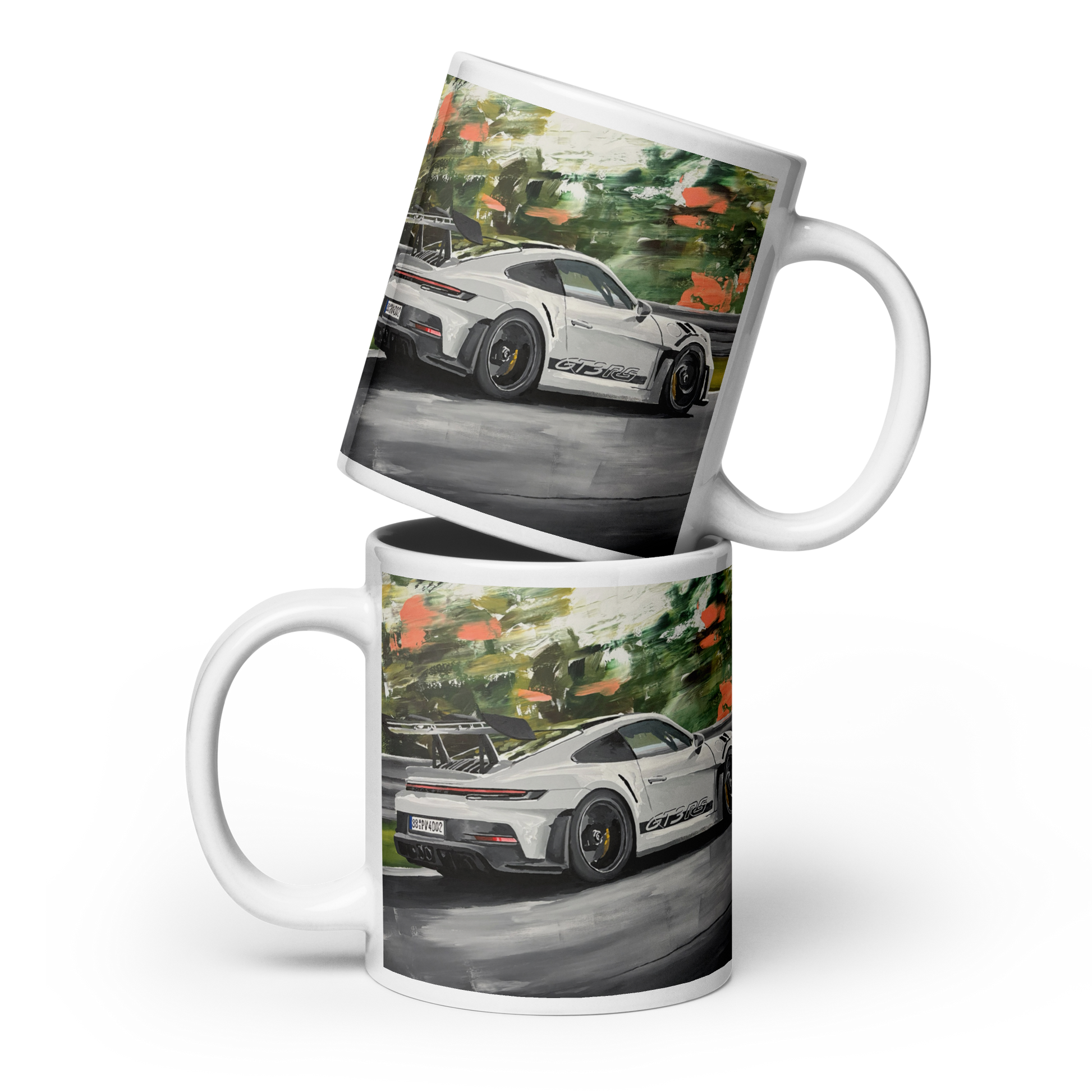 Two white ceramic mugs stacked and overlapping, printed with a colorful artistic depiction of a white sports car on a road with green trees and orange foliage. Daniel Maltzman original desgn.