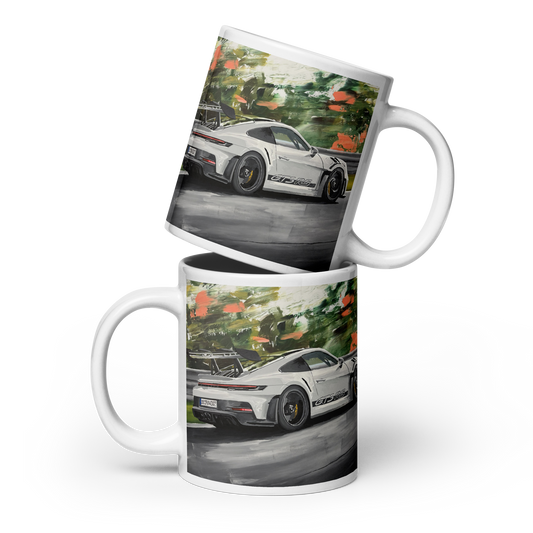 Two white ceramic mugs stacked and overlapping, printed with a colorful artistic depiction of a white sports car on a road with green trees and orange foliage. Daniel Maltzman original desgn.