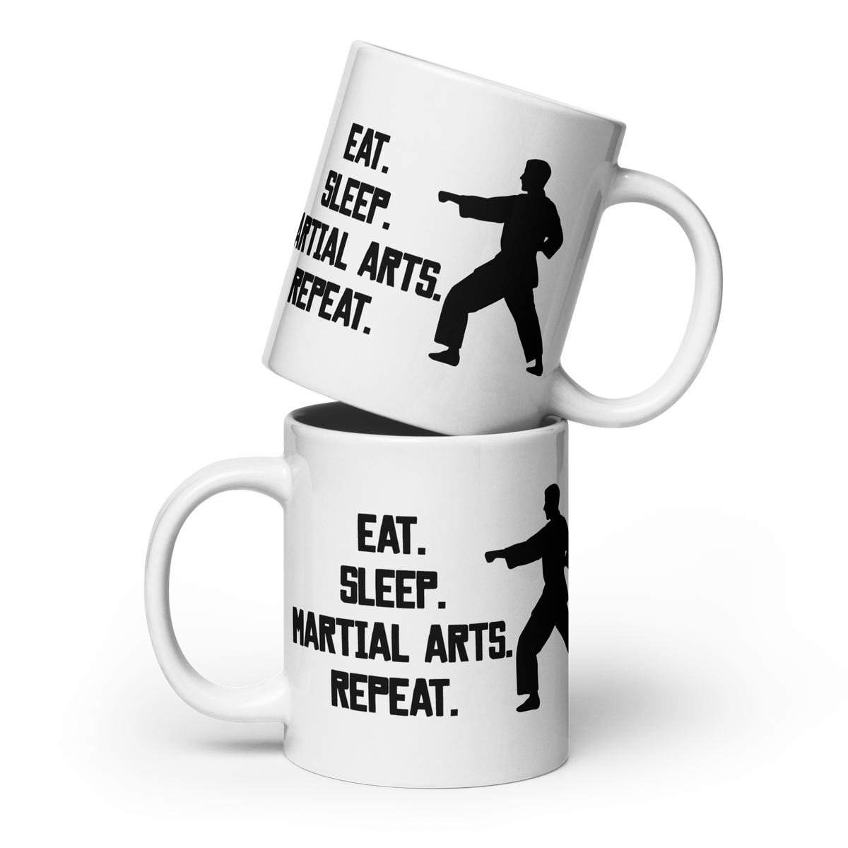 Two stacked white ceramic mugs with black printed text reading 'EAT. SLEEP. MARTIAL ARTS. REPEAT.'