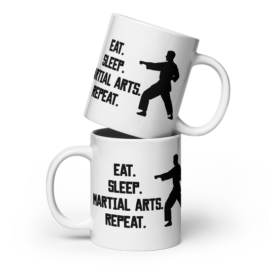 Two stacked white ceramic mugs with black printed text reading 'EAT. SLEEP. MARTIAL ARTS. REPEAT.'