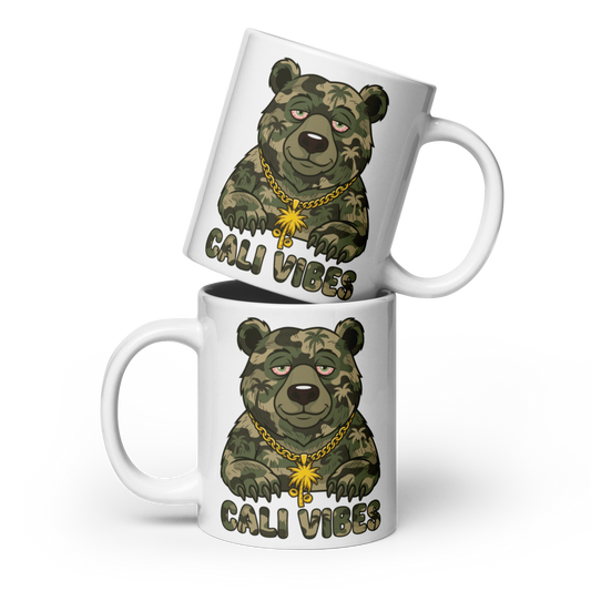 Two white ceramic mugs stacked diagonally, featuring a cartoon grizzly bear printed in green camouflage with a gold chain and the text 'CALI VIBES' below it.