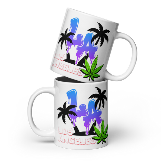 Two stacked white ceramic mugs with a colorful Los Angeles graphic design featuring a blue and purple dripping 'LA' monogram, black palm trees, a green cannabis leaf, and pink 'LOS ANGELES' text.