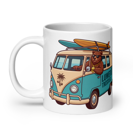 A white ceramic coffee mug featuring a colorful cartoon illustration of a brown bear driving a retro turquoise and beige van with a surfboard on top. The side of the van reads 'LOWER TRESTLE'.