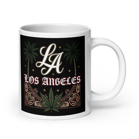 A white ceramic mug featuring a black wraparound graphic design with the text 'LA Los Angeles' in white and red, flanked by palm trees, stars, paisley patterns, and a green cannabis leaf.