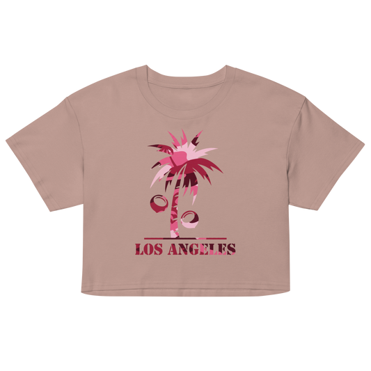 A cropped short-sleeve t-shirt in a dusty rose pink color, featuring a graphic of a palm tree with pink and red geometric shapes and the text 'LOS ANGELES' printed below it, displayed on a solid white background.