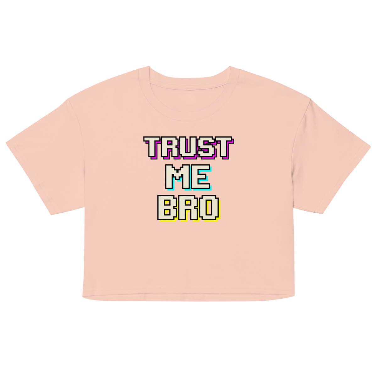 A light peach-pink short-sleeve crop top t-shirt featuring a retro pixelated graphic on the chest that reads 'TRUST ME BRO' in white text with colorful neon-style outlines.