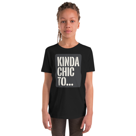 A young girl with braided hair wearing a black t-shirt with a gray graphic that reads 'KINDA CHIC TO...'.