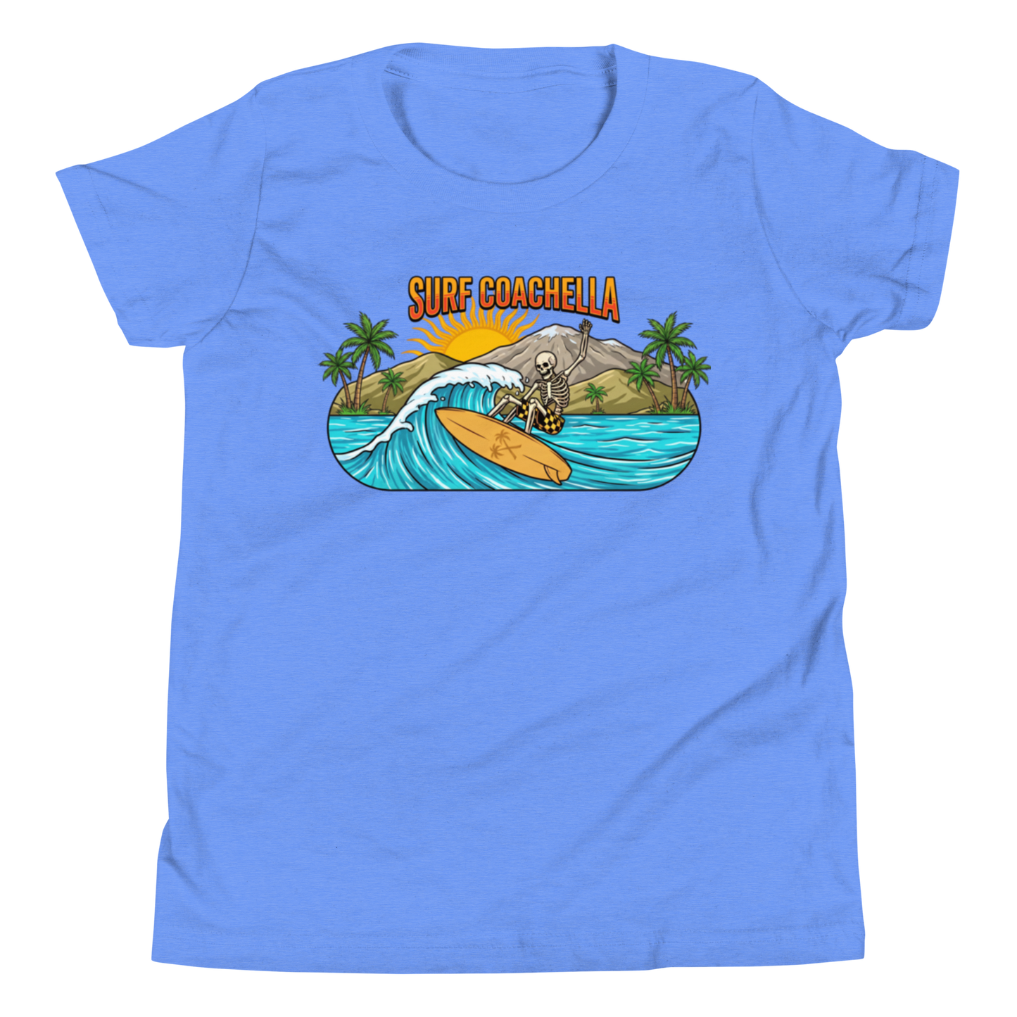 A light blue short-sleeve crewneck t-shirt featuring a colorful graphic print on the chest. The graphic shows a skeleton surfing on an orange surfboard with a wave, mountains, palm trees, and the text 'SURF COACHELLA' in orange and yellow.