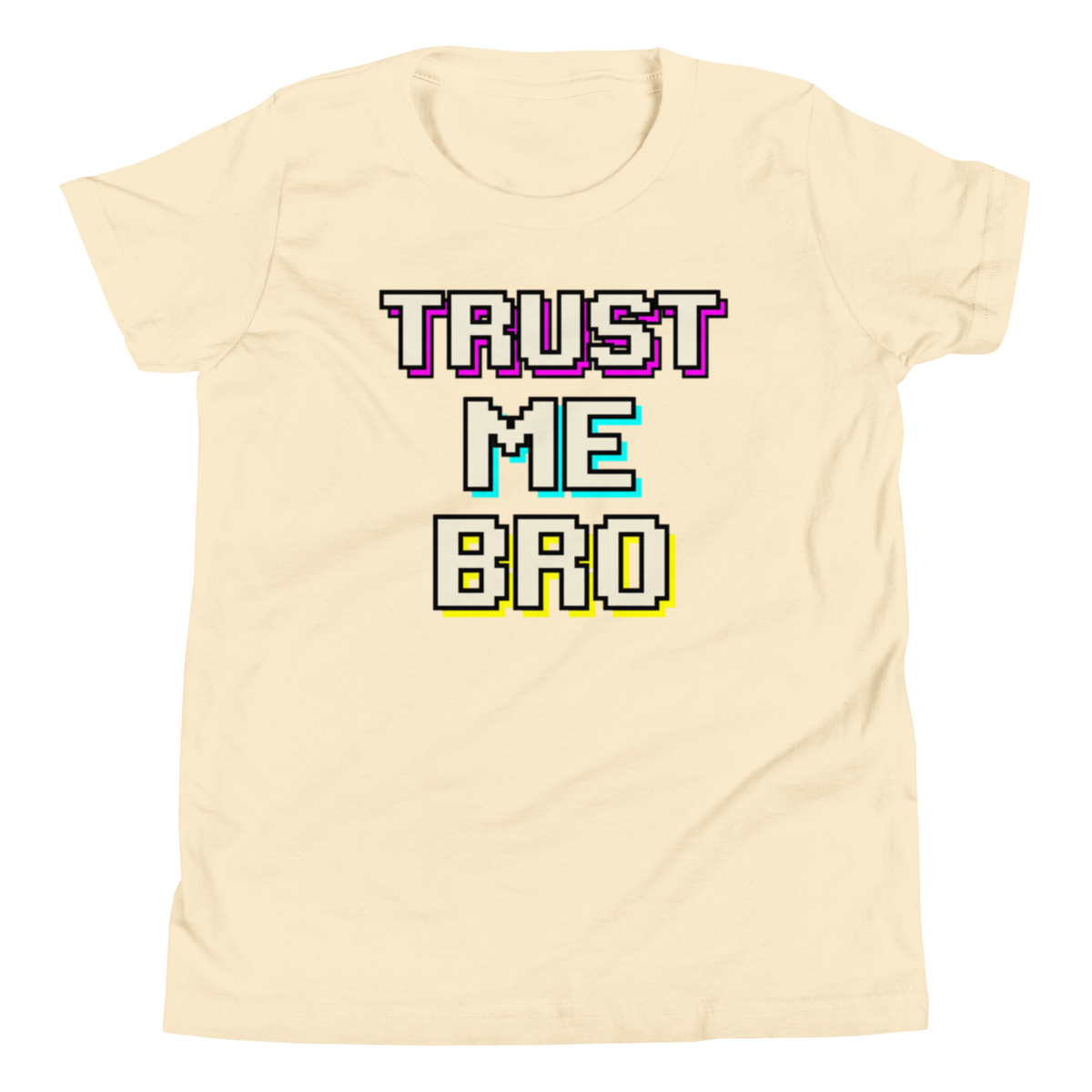 A cream-colored short-sleeve t-shirt with a retro pixelated graphic reading 'TRUST ME BAD' in white letters with purple, cyan, and yellow outlines, displayed on a clean white background.