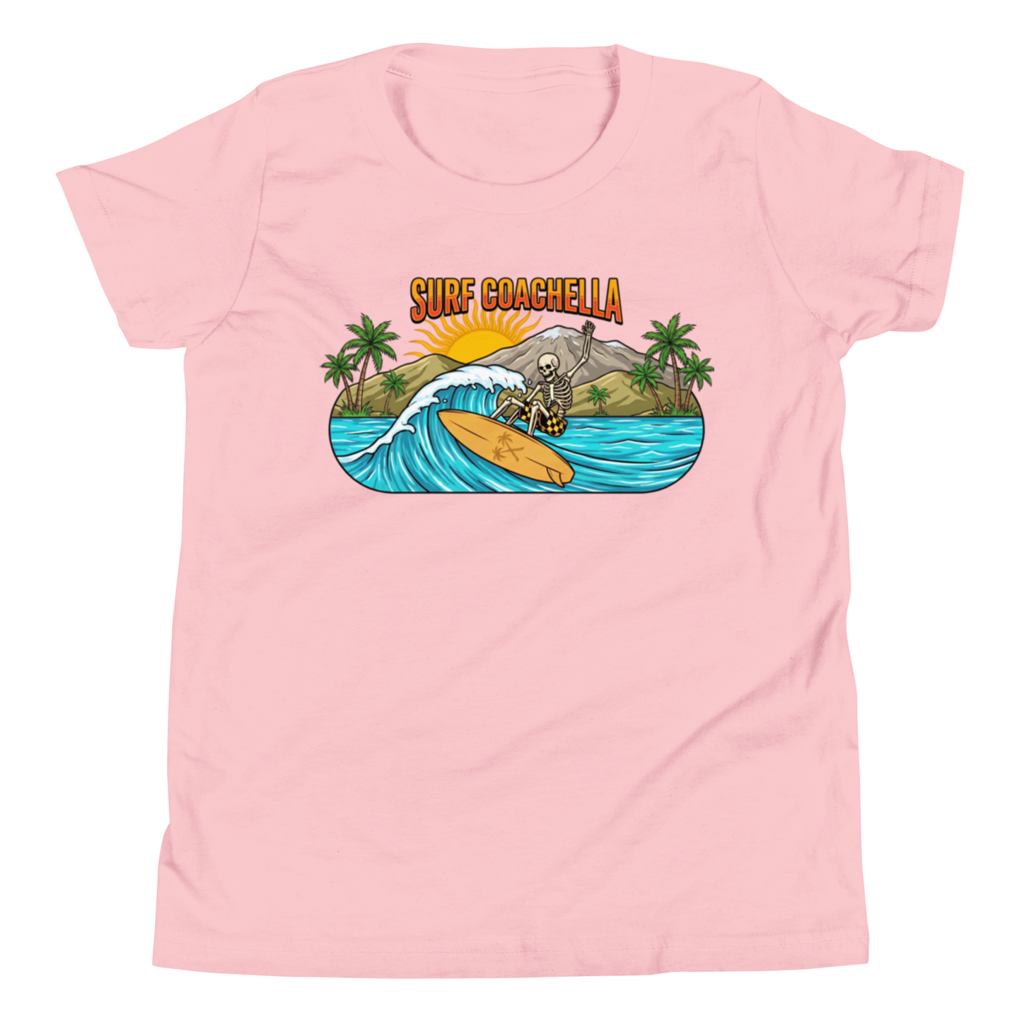A light pink short-sleeve crewneck t-shirt featuring a colorful graphic print on the front. The graphic depicts a skeleton surfing on a wave with palm trees, mountains, and the text 'SURF COACHELLA' in orange.