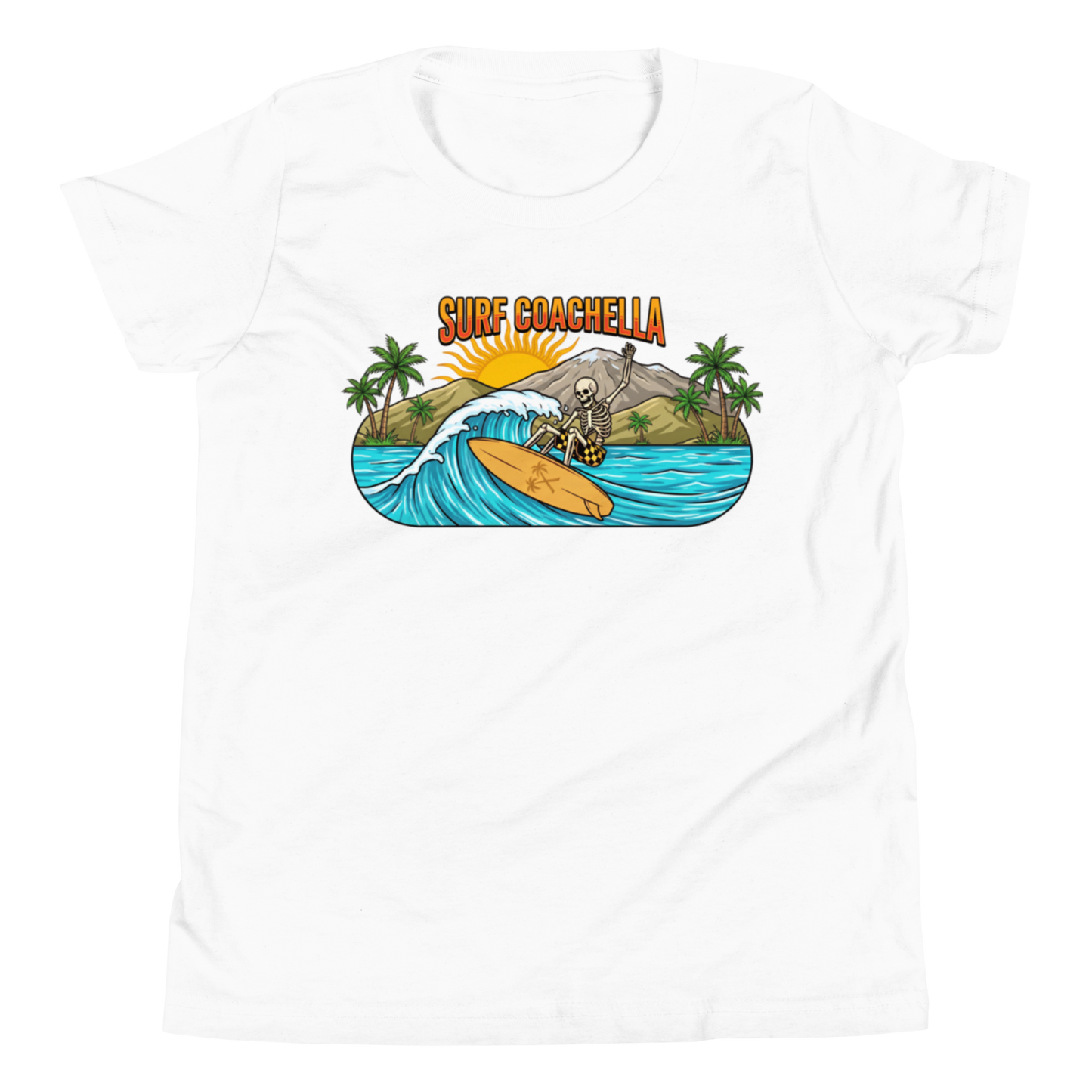 A white short-sleeve crewneck t-shirt featuring a colorful graphic print on the chest. The graphic depicts a skeleton surfer riding a wave on a yellow surfboard, with palm trees, a gray shark, and the text 'SURF COACHELLA' in orange and yellow.